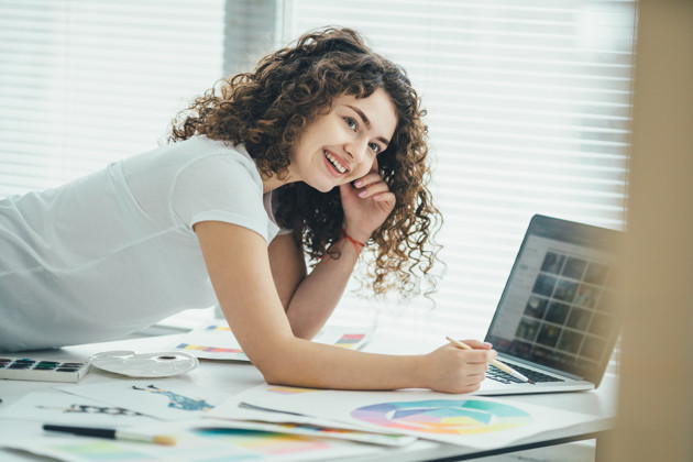 Kvinde ved bord med pc og farver