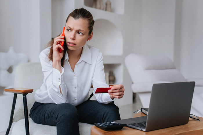 Worried Businesswoman Talks By Phone With Bank